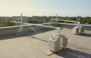 Counter weight or weight balance concrete blocks or bricks as part of suspended wire rope platform for facade works on high multistorey buildings. Many blocks with metal handles photo