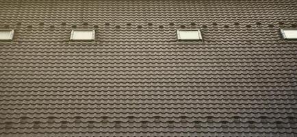 The texture of the roof with a roof made of metal, covered with drops from the rain. Several pane windows are built into the roof photo