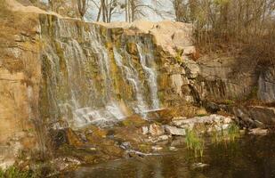 Beautiful waterfall between large rocks in autumn forest. Sofievskiy park in Uman, Ukraine photo