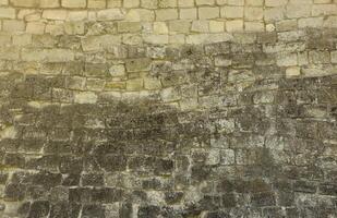 Very old brick stone wall of castle or fortress of 18th century. Full frame wall with obsolete dirty and cracked bricks photo