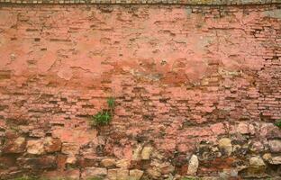 Very old damaged red brick wall with boneless bricks and cement mortar photo