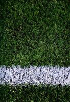 White stripe on a bright green artificial grass soccer field photo