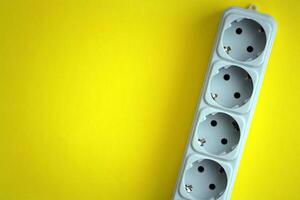 White electrical multi plug extender with european socket on bright yellow background photo