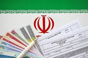 Iranian annual income tax return form F20-25-006 ready to fill on table with pen and iranian money on flag photo