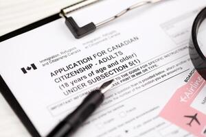 Application for Canadian citizenship for adults on A4 tablet lies on office table with pen and magnifying glass photo