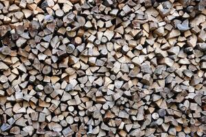 Firewood stacked near the wooden wall of old hut. Many chopped logs of firewood photo