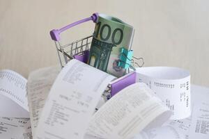 Euro bills bunch in shopping trolley surrounded by many paper receipts photo