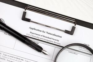 N-400 Application for Naturalization blank form on A4 tablet lies on office table with pen and magnifying glass photo