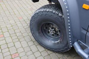 Wheel closeup in a countryside landscape with a mud road. Off-road 4x4 suv automobile with ditry body after drive in muddy road photo