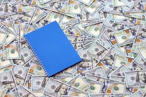 Office workplace table with blank notebook or notepad and many hundred dollar bills photo