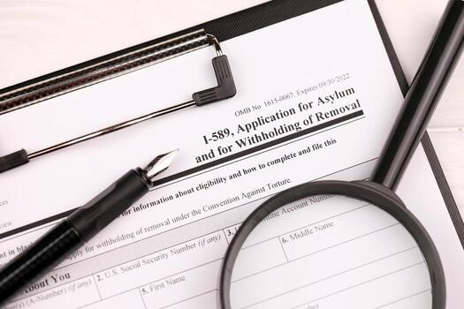 I-589 Application for asylum and for withholding of removal blank form on A4 tablet, lies on office table with pen and magnifying glass photo