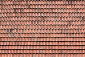 Close up of red terracotta roof shingles with some mildew. Background texture of roofing material photo