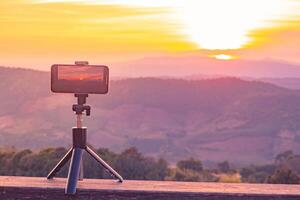 A smartphone is recording the sun setting over a mountain range. photo