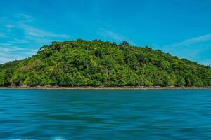 Aerial panorama of Thailand's verdant, lush tropical island, National Park Island, with blue and aquamarine the sea, and clouds shining by sunlight in the background. photo