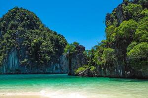 Aerial panorama of Thailand's verdant, lush tropical island, National Park Island, with blue and aquamarine the sea, and clouds shining by sunlight in the background. photo