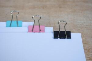 Side view of blank document papers with paper clips pastel on wooden table. Documentation concept photo