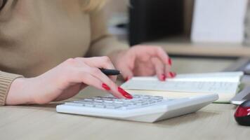 handen van een vrouw accountant berekenen Aan een rekenmachine en maken een binnenkomst in een notitieboekje video