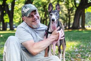 un maduro calvo hombre con su galgo foto