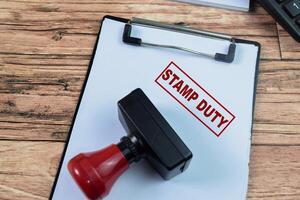 Red Handle Rubber Stamper and Stamp Duty text above paperwork isolated on wooden background photo