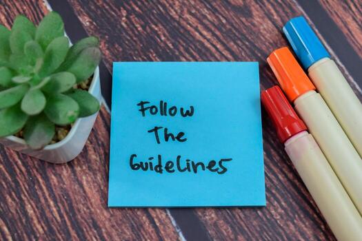 Concept of Follow the Guidelines write on sticky notes isolated on Wooden Table. photo