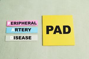 Concept of PAD - Peripheral Artery Disease write on sticky notes isolated on Wooden Table. photo