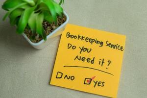 Concept of Bookkeeping Service, Do You Need it write on sticky notes isolated on Wooden Table. photo