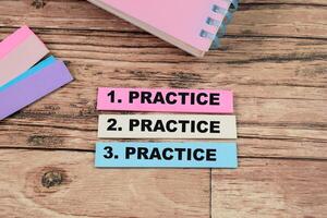 Concept of Practice, Practice, Practice write on sticky notes isolated on Wooden Table. photo