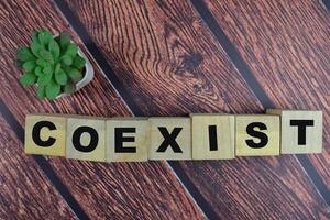 Concept of The wooden Cubes with the word Coexist on wooden background. photo