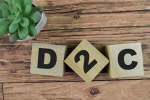 Concept of The wooden Cubes with the word D2C - Direct to Consumer on wooden background. photo