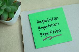 Concept of Repetition, Repetition, Repetition write on sticky notes isolated on Wooden Table. photo