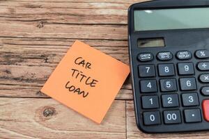 Concept of Car Title Loan write on sticky notes isolated on Wooden Table. photo