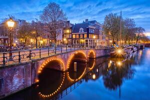 Ámsterdam canal, puente y medieval casas en el noche foto