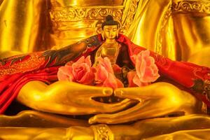 Small Buddha Sakyamuni statue in hands of large photo