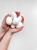 Hands cradling a cluster of white eggs against pale background, a symbol of care, nourishment, and new beginnings with ample copy space. For culinary websites, recipe blogs, and nutritional guides. photo