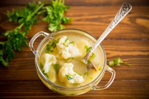 cooked chicken soup with cauliflower and vegetables in a bowl photo