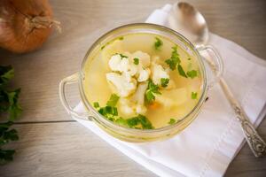 cooked chicken soup with cauliflower and vegetables in a bowl photo