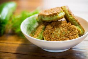 fried zucchini pancakes with herbs, in a plate . photo