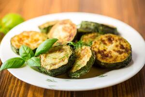 zucchini fried in circles with spices and herbs, in a plate . photo