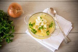 cooked chicken soup with cauliflower and vegetables in a bowl photo