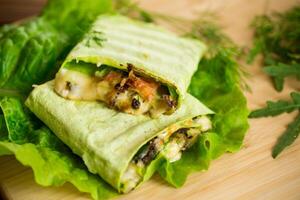 green hot vegetarian pita bread with mushrooms and different vegetables, with lettuce leaves . photo