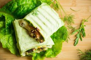 green hot vegetarian pita bread with mushrooms and different vegetables, with lettuce leaves . photo