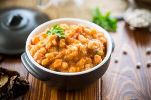 beans stewed with vegetables and spices, in a bowl . photo