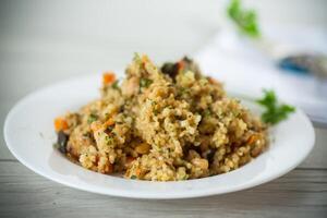 cooked bulgur with vegetables, carrots and dried mushrooms in a plate . photo