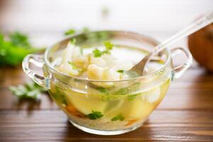 cooked chicken soup with cauliflower and vegetables in a bowl photo