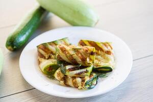 Grilled zucchini pieces with garlic sauce in a white plate. photo