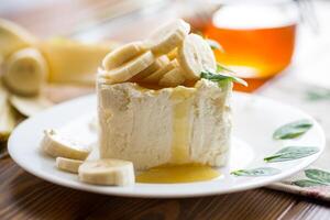 Portion of homemade milk curd with banana slices and honey photo