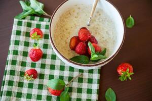 cooked diet oatmeal in a bowl with fresh ripe strawberries photo