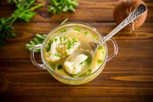 cooked chicken soup with cauliflower and vegetables in a bowl photo