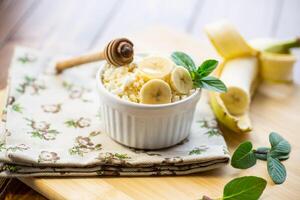 desmoronadizo orgánico cabaña queso con miel y bananas en un cerámico cuenco foto