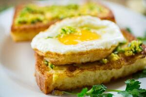 Fried croutons in batter with garlic and herbs and a fried egg in a plate. photo